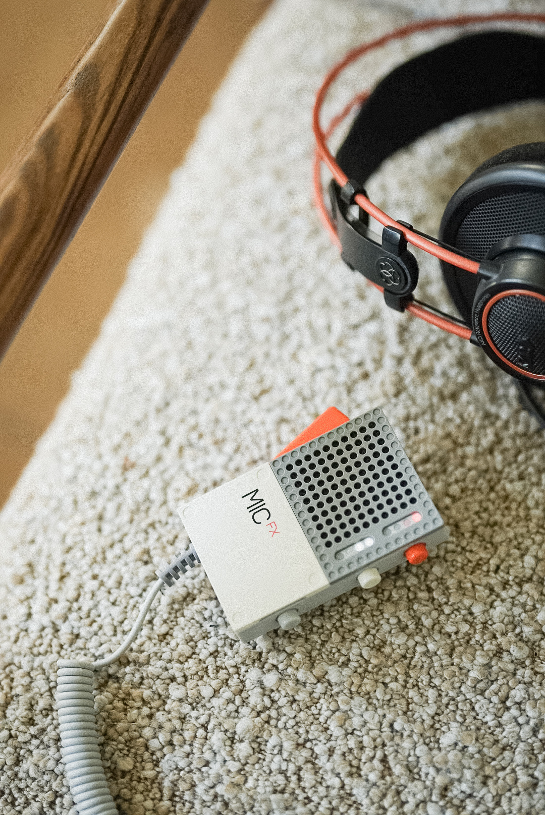 Mikrofon Teenage Engineering EP-2350 z napisem MIC FX na jasnym fotelu, obok słuchawki AKG z czerwonym pałąkiem